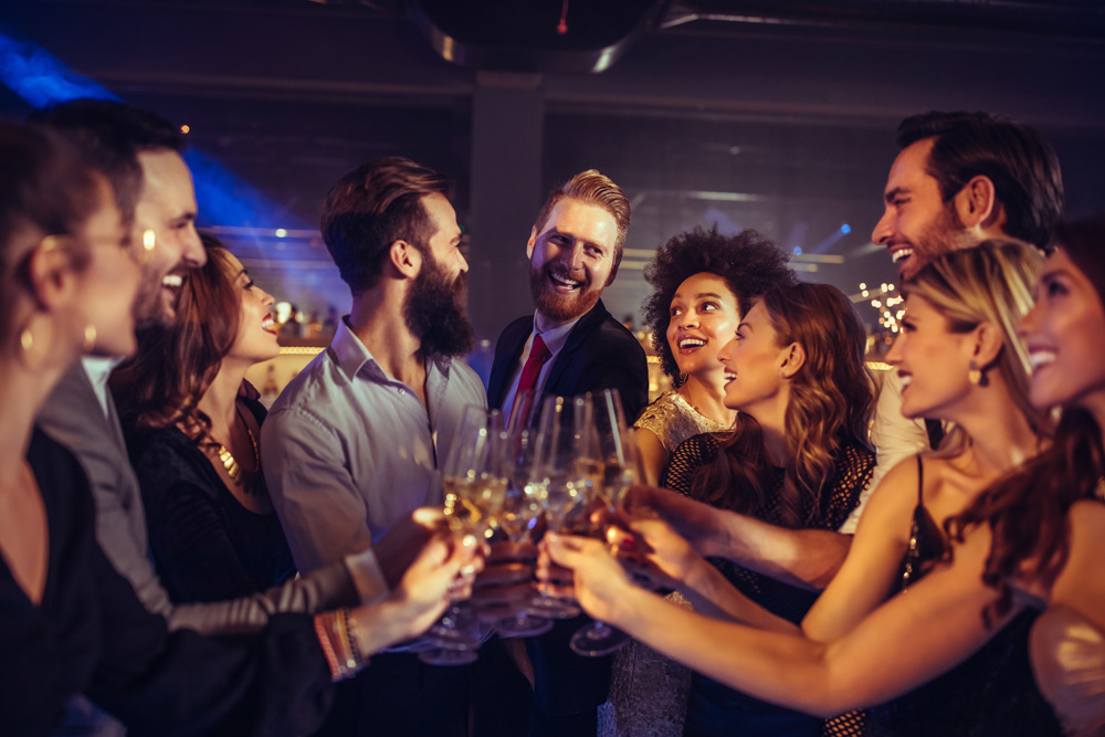 Friends happily toasting with drinks at a lively party.