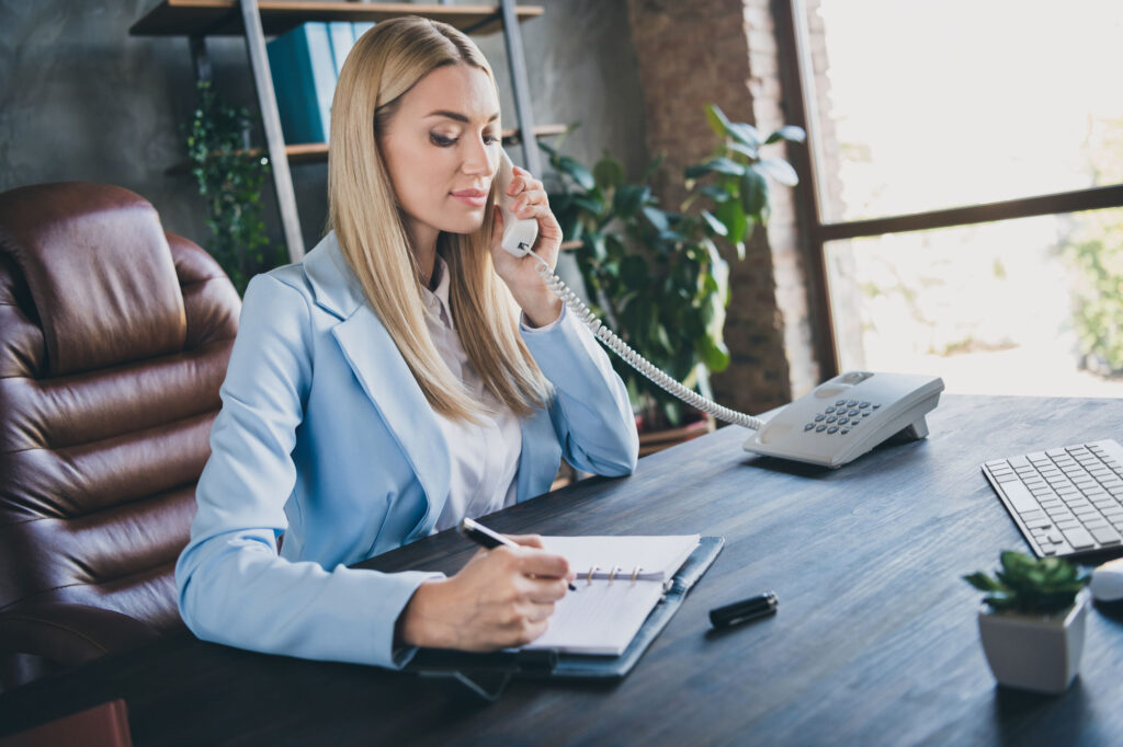 Professional woman on phone, taking notes in office.